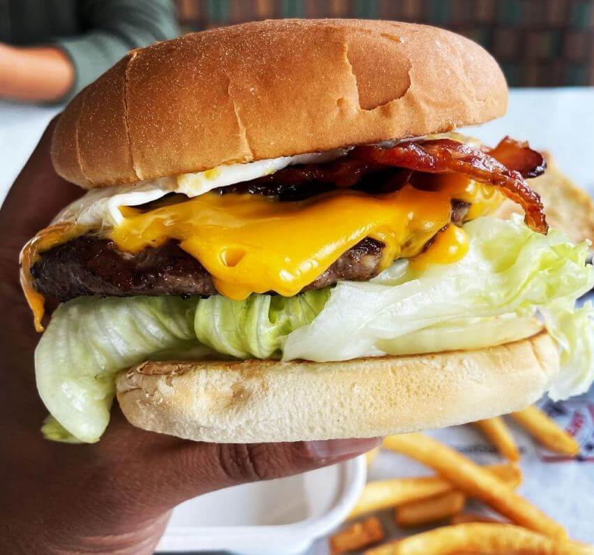 Hand holding a bacon egg and cheeseburger