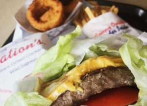 closeup of a cheese burger, onion rings and fries